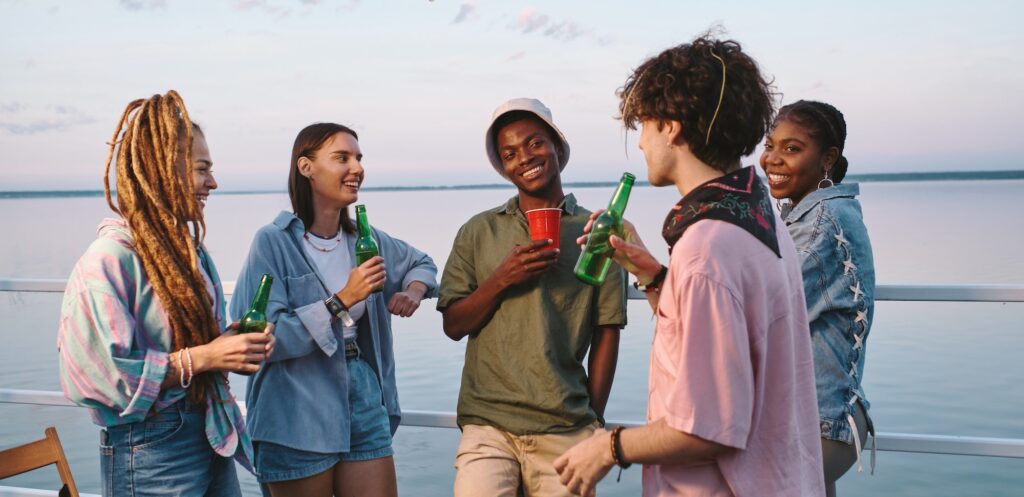 Happy multiracial friends with drinks enjoying outdoor party